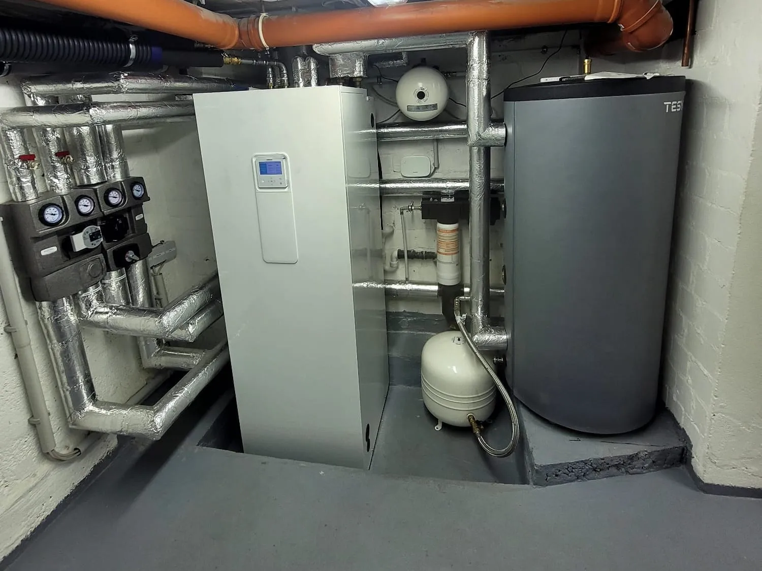 Heizungsanlage mit Warmwasserspeicher und gedämmten Rohrleitungen im Keller